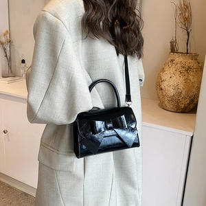 Sac à main élégant en cuir verni noir avec un grand nœud décoratif et une bandoulière