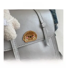 Detail view of grey PU leather bag with embroidered animal patch and neat stitching