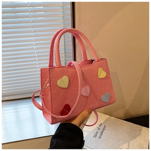 Gros plan détaillé d'un sac à main rayé rose avec des écussons cœurs colorés au soleil