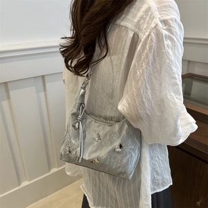 Sac à épaule argenté avec décorations papillon et texture plissée sur modèle