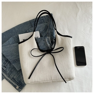 Détail du sac cabas en lin à chevrons avec nœud noir et bordure en cuir