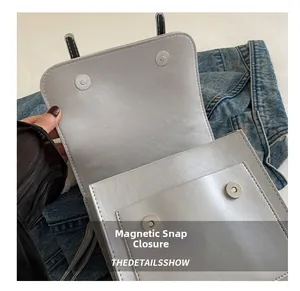 Close-up of dual magnetic metal closures on a silver-grey faux leather shoulder bag