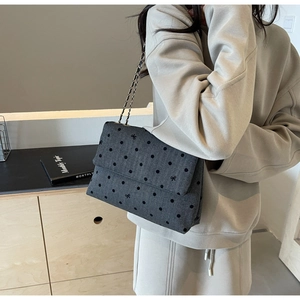 Sac bandoulière en denim gris avec broderies nœuds et chaîne porté par un mannequin