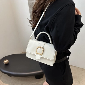 Sac à main blanc minimaliste avec boucle dorée et bandoulière porté par un mannequin