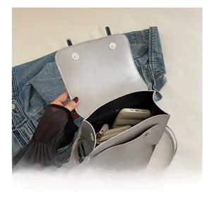 Top view detail of grey leather crossbody bag showing spacious interior with phone and wallet