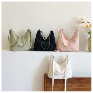 Détail de sacs fourre-tout texturés en vert, noir, rose et blanc avec des chaînes métalliques