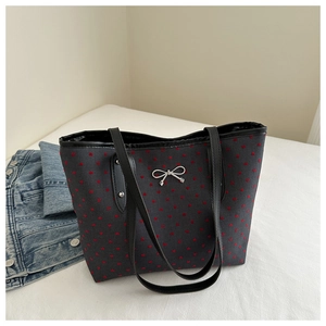 Close-up of a grey canvas tote bag featuring red heart patterns and a silver bow detail