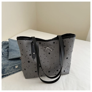 Detail of silver metal bow accessory on gray canvas tote bag with star patterns
