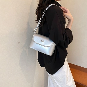 Silver shoulder bag with golden bow buckle on minimalist black and white outfit