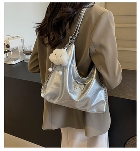 Close-up of silver tote bag with butterfly metal detail and plush cloud pendant