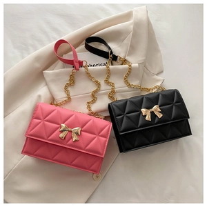 Dettaglio di borse trapuntate rosa e nere con fibbie a fiocco dorato su un blazer beige