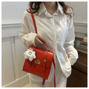 Detail of red leather bag with dog embroidery and fluffy white plush charm