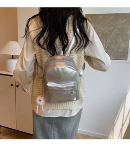 Rear view of a silver metallic PU backpack featuring a cute pink pom-pom keychain detail