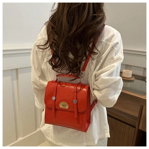Detailed back view of a red faux leather backpack with cartoon dog embroidery on a model