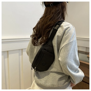 Détail de la sangle réglable et boucle rapide sur un sac de poitrine noir en nylon
