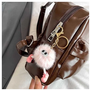 Close-up of brown polished leather backpack with gold zippers and pink monster charm