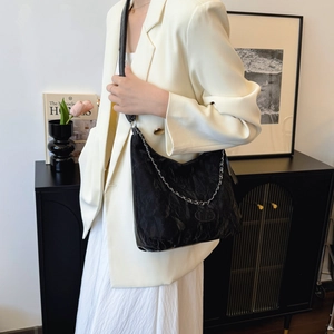 Grande borsa tote in pelle nera a pieghe con catena d'argento in un contesto lifestyle