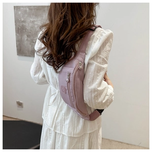 Détail du sac bandoulière en nylon violet imperméable avec plusieurs poches zippées