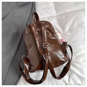 Detailed back view of brown PU leather backpack with metal buckles and heart charm