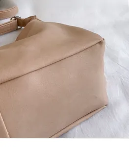 Close-up of beige leather tote bag side view with detailed stitching and pebbled texture