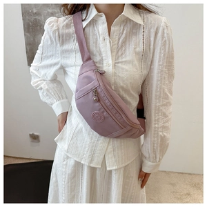 Détail du sac bandoulière en nylon lilas avec zips multicouches et logo sportif