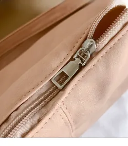 Detailed macro shot of the smooth silver metal zipper on a solid beige tote bag