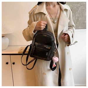Close-up of black PU leather backpack texture and heart charm held by a model