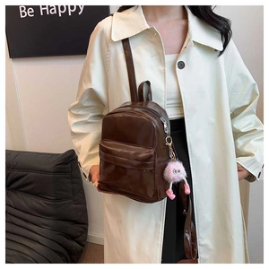 Brown PU leather mini backpack with a pink furry charm shown on a casual female model