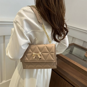 Borsa a tracolla trapuntata beige con fibbia a fiocco dorato e catena su una modella