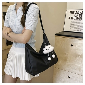 Detail of a large black faux leather tote bag featuring a cute white cloud plush pendant