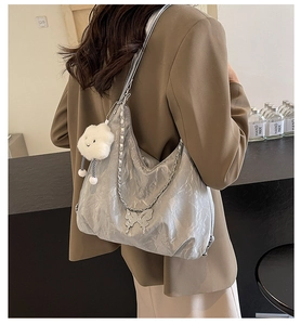 Detail of silver metallic tote bag with crinkled texture, butterfly charm and cloud keychain