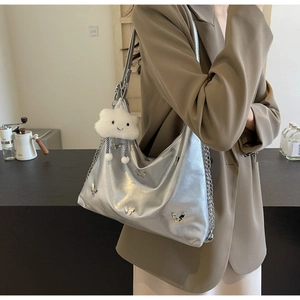 Close-up of metallic silver tote bag featuring 3D butterfly charms and cloud pendant
