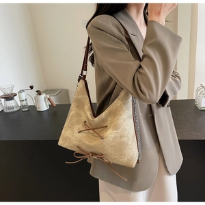 Dettaglio borsa tote vintage con lacci in pelle e tracolla a catena argentata