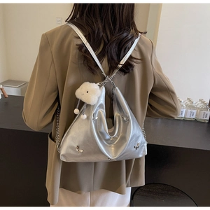 Silver metallic tote bag detail with 3D butterfly hardware and fluffy charm pendant
