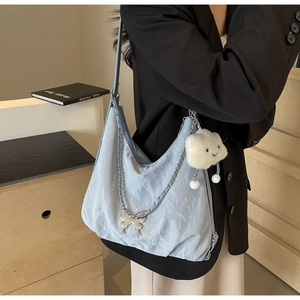 Detail of light blue tote bag with silver butterfly buckle and white cloud plush charm