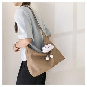Brown litchi grain leather tote bag with cloud plush charm shown on model shoulder