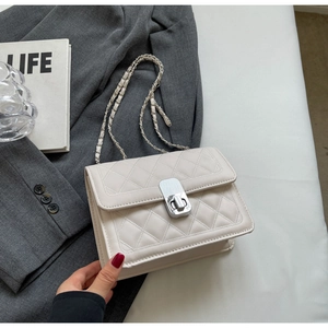 Borsa in pelle beige trapuntata con tracolla a catena su sfondo minimalista