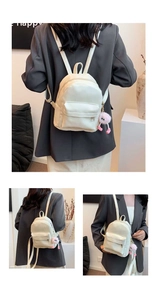 Detail of cream mini PU leather backpack featuring adjustable straps and plush monster charm