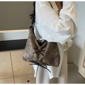 Dettaglio borsa a tracolla marrone vintage con lacci incrociati e fiocco decorativo