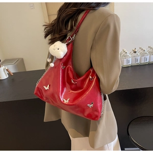 Detail of red glossy tote bag with metal butterfly buckles and white cloud charm