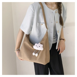 Detail of khaki hobo tote bag with lychee texture and cute white plush cloud charm