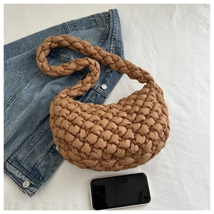 Détail de la texture froncée du sac hobo marron avec large bandoulière et smartphone
