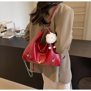 Detail of red leather tote bag with silver butterfly clips and a white cloud charm accessory