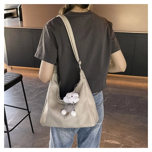 Detail of a large beige leather tote bag with a cloud charm on a model shoulder