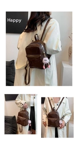 Detail view of brown PU leather backpack featuring a cute pink plush monster charm