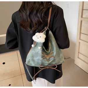 Dettaglio della borsa tote verde scuro con lacci decorativi e ciondolo a forma di nuvola