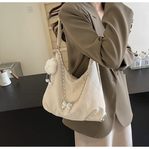 Detail of cream crescent tote bag with silver chain, butterfly charm and cloud plush toy