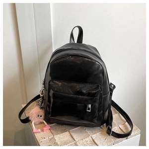 Detail view of black oily PU leather backpack with a pink monster charm on a stone base