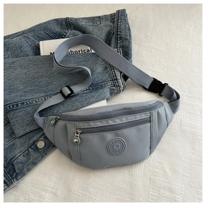 Détail d'un sac banane en nylon bleu clair avec logo sport sur fond blanc texturé