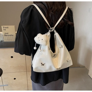Close-up of a white hobo bag with silver butterfly charms and a plush cloud keychain